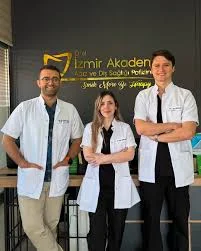 Three members of the İzmir Akademi dental team in front of the clinic's branded wall